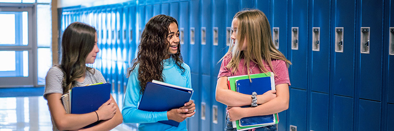 Three girls walking and talking in hallway