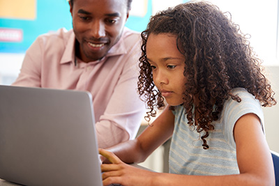 child at computer with parent watching