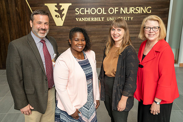 VUSN faculty in front of wood wall with VUSN logo