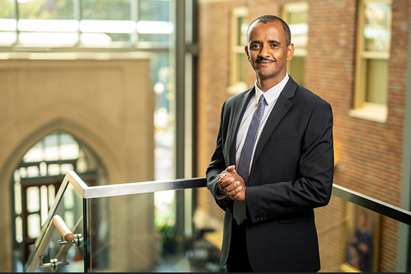 New faculty member Mulubrhan Mogos stands on the staircase landing in the CW Atrium