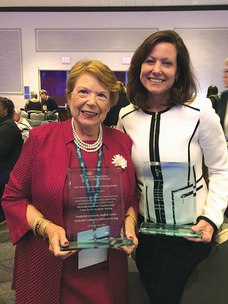 Dean Norman and Alumna/Faculty April Kapu hold glass awards