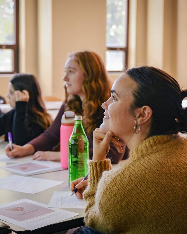 student smiling in classroom with other students at table