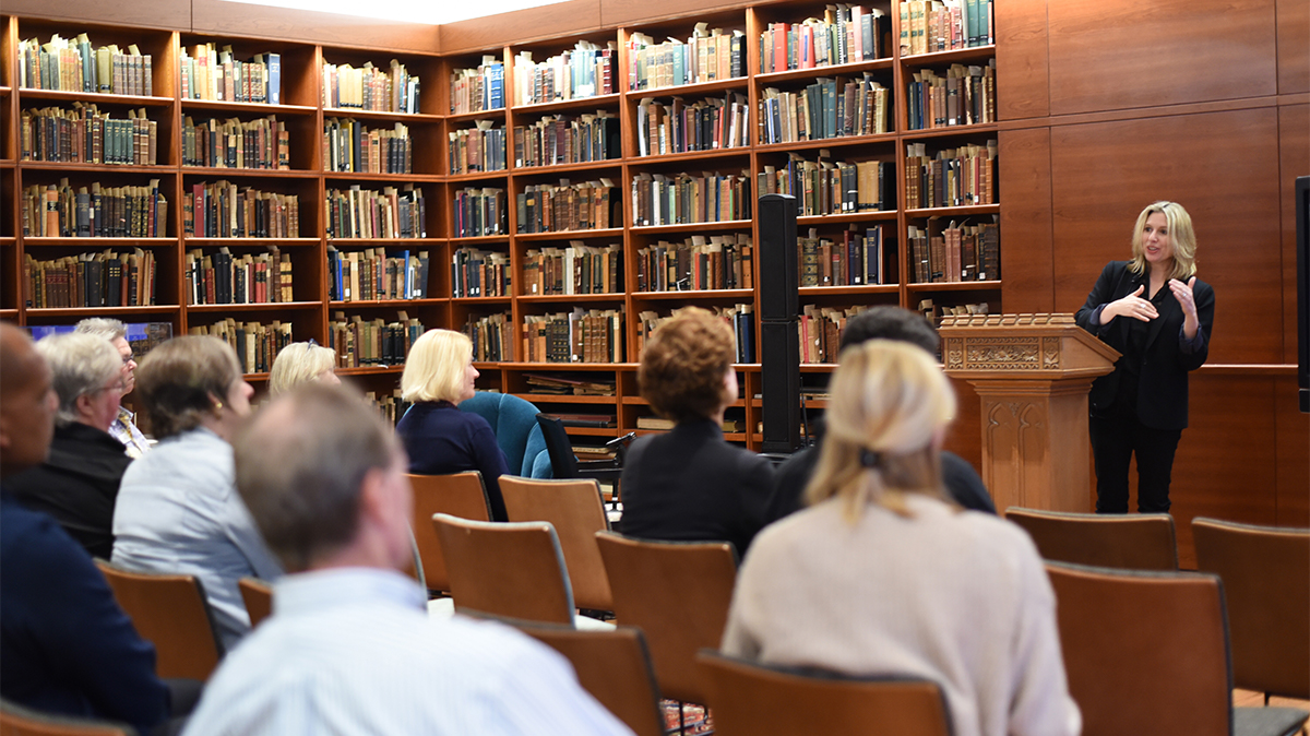 holly tucker speaks in front of a crowd of faculty members