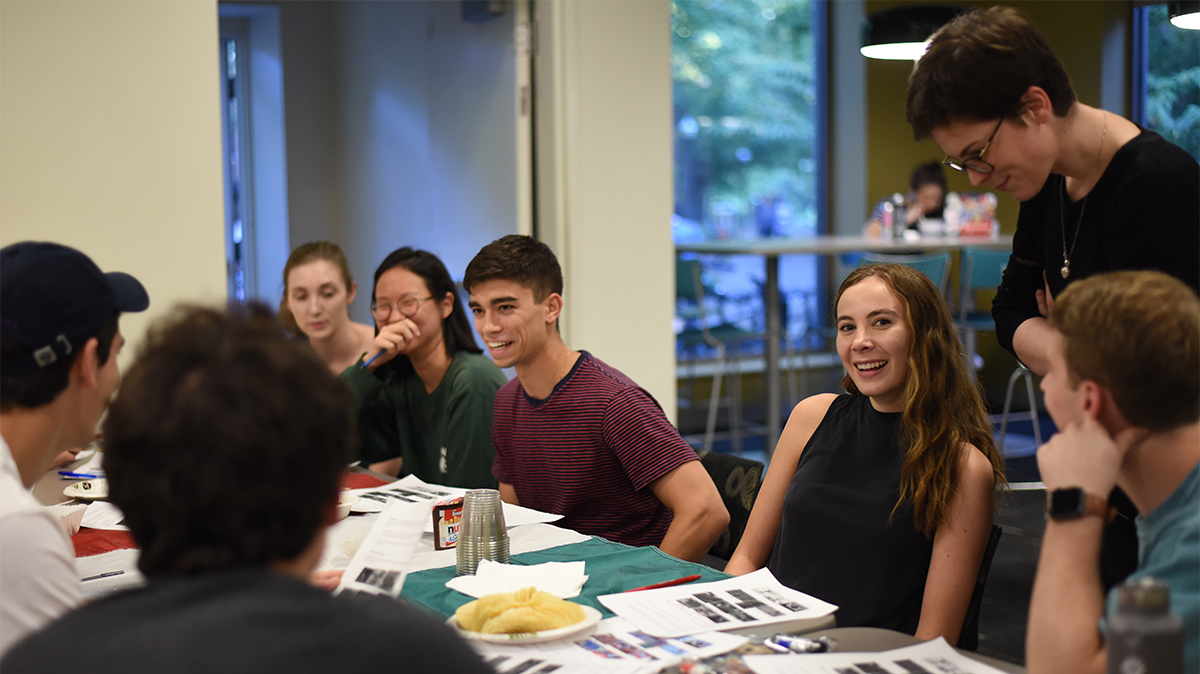 several students gathered around a table while a professor looks on
