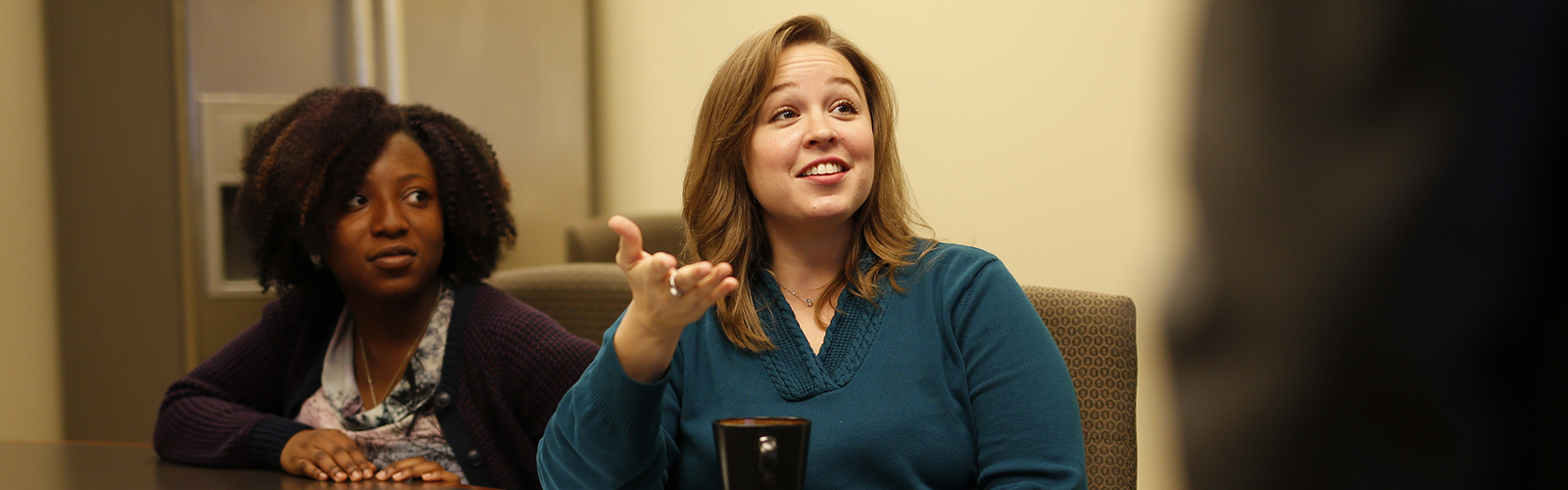 two graduate students at a table in a conference room