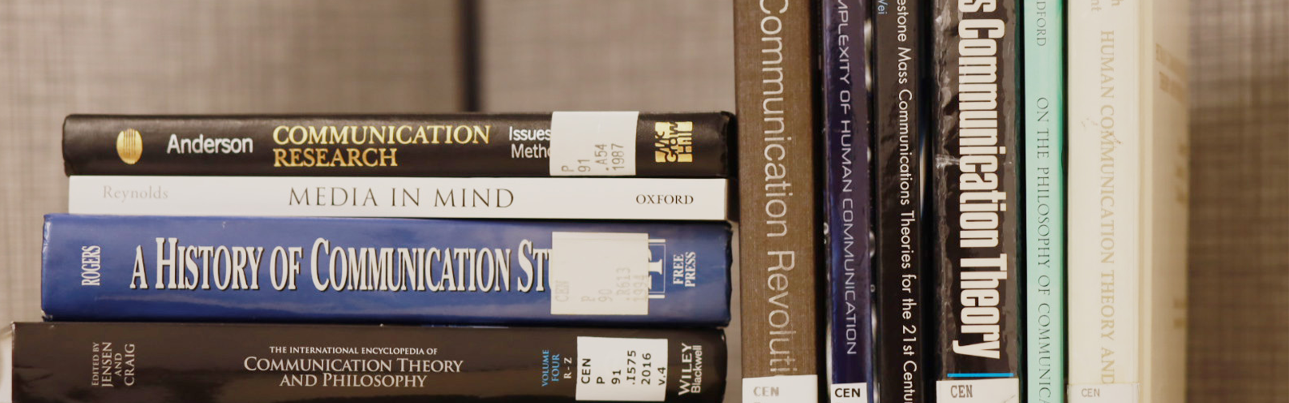 a stack of books next to a row of books on communication studies