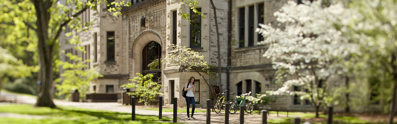 exterior of Furman Hall on Vanderbilt campus with flowering white dogwood tree in foreground and student walking by