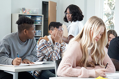 sam rubbing his eyes at his desk