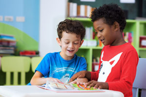 Two boys reading book together