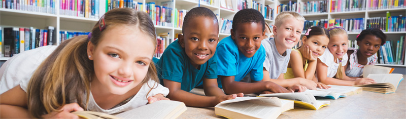 Line of children smiling while reading at table