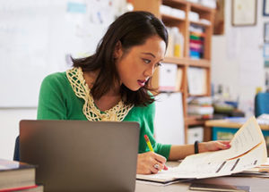 Woman taking notes while looking at paper report