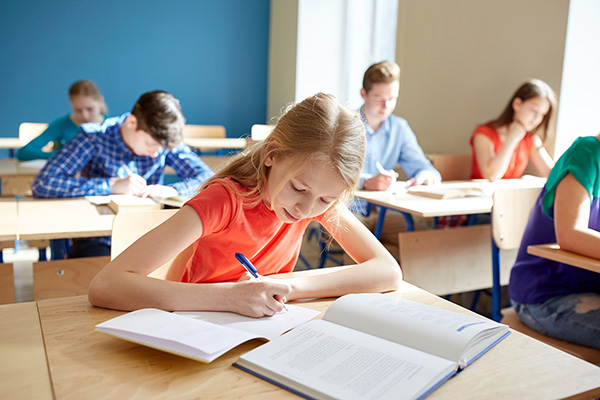 student writing in notebook at desk