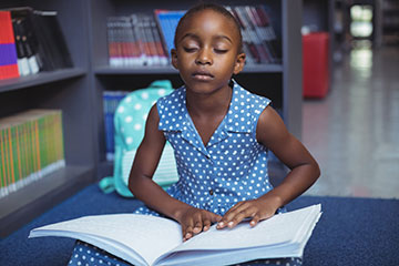 visually impaired student reading a braille book