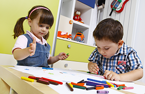 two children working with markers at table
