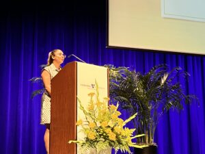 A woman stands behind a lectern to speak