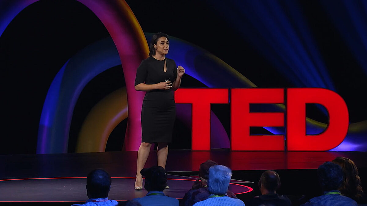 Betül Kaçar, in a black dress, on the TED stage.