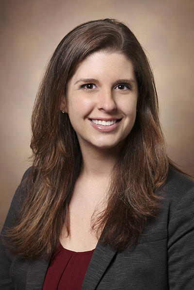 Photo of young woman wearing a dark grey coat and maroon top.