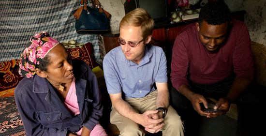 Justin Banerdt and Biruk Nidaw interviewing a beneficiary in her home about her experience with a basic income grant program.