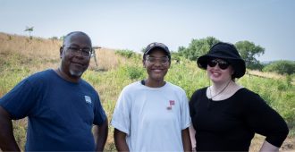a man and two women stand against a hill
