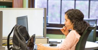 student working on computer while talking into a microphone