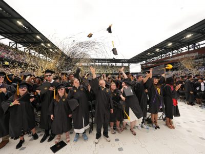 Vanderbilt graduates in a stadium with yellow streamers flying overhead
