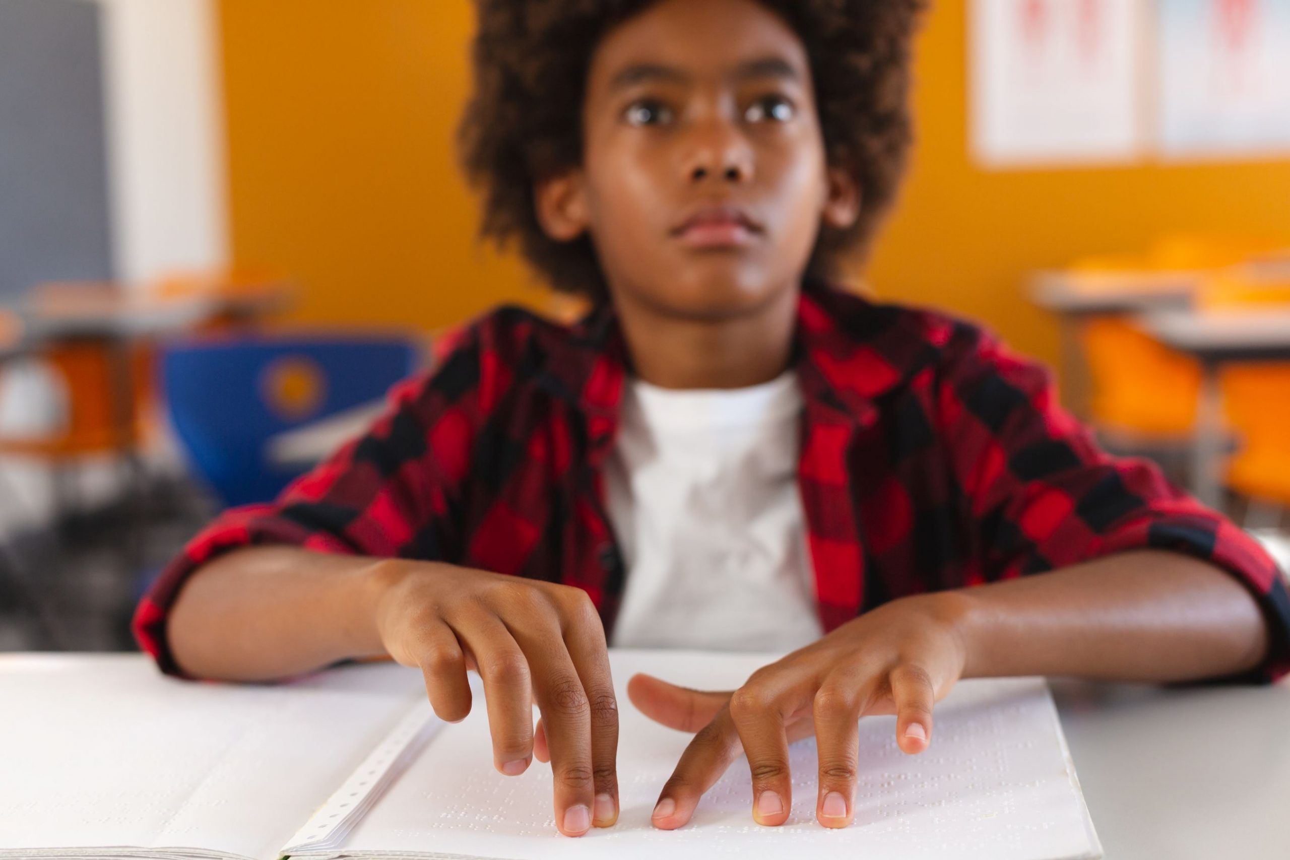 A male visually impaired student uses his hands to read braille.