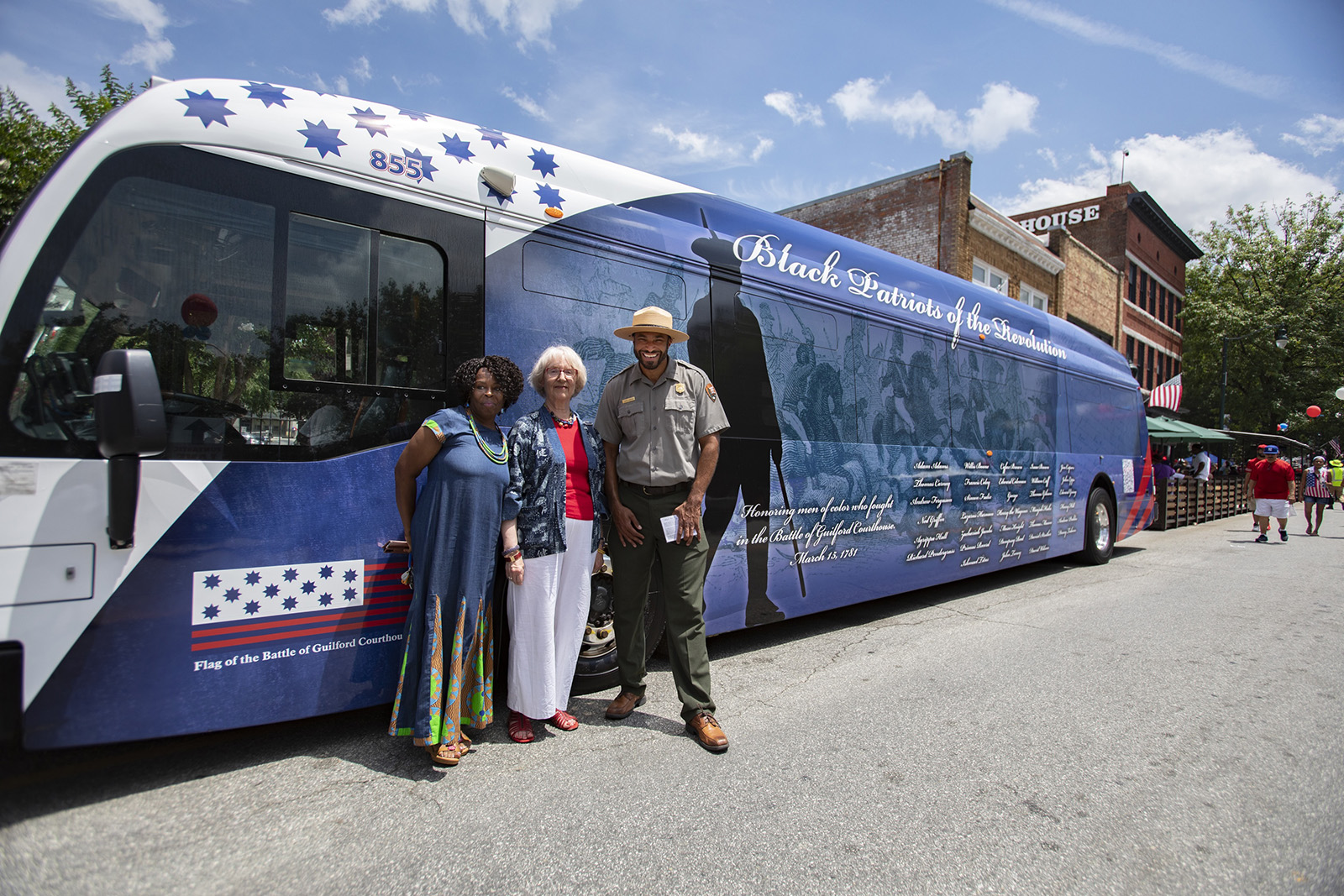 Sage Chioma, Joanna Foley and Aaron LaRocca with Greensboro (N.C.) bus with names of African Americans who fought in the Battle of Guilford Courthouse during the American Revolution.