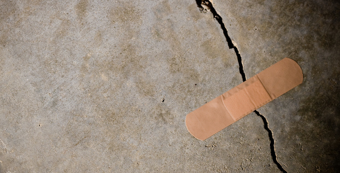 Adhesive bandage holding together a splitting concrete wall. (Concept: termporary solution) Tight/shallow DOF on bandage.