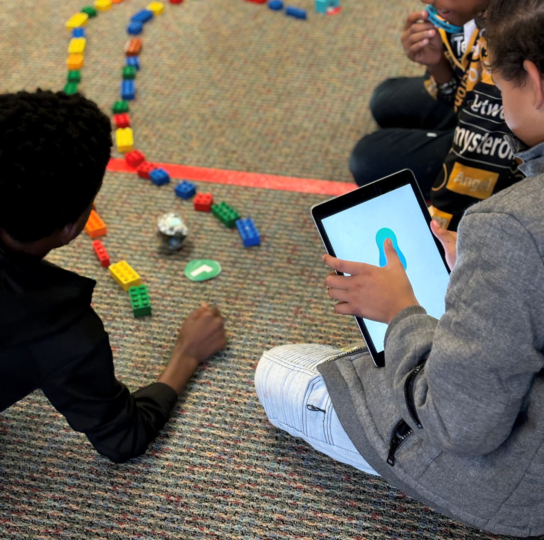 Children play a game using an iPad and blocks