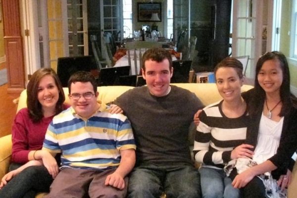 A group of young adults and adults sit on a sofa