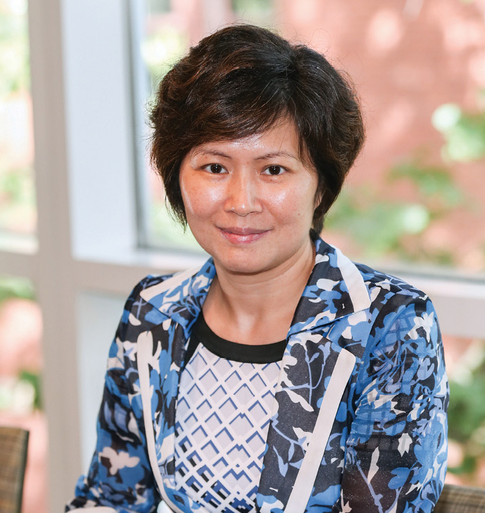 Xiaoyan Jiang in printed blue suit sitting in front of a window