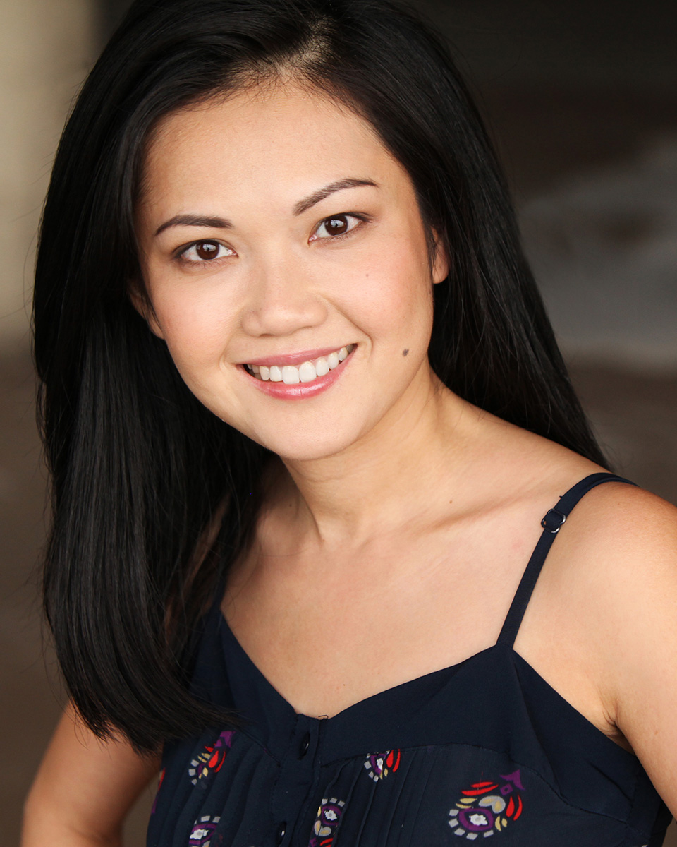 Portrait shot of a young woman with long black hair wearing a sleeveless black dress.