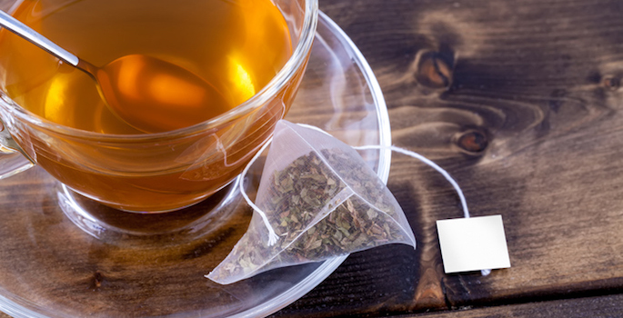 green tea in glass mug with tea bag on the saucer