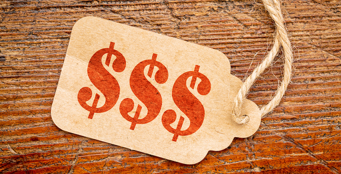 red stencil $$$ on a paper price tag against rustic wood