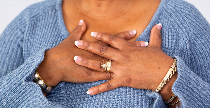 older overweight African American woman holding hands over her heart