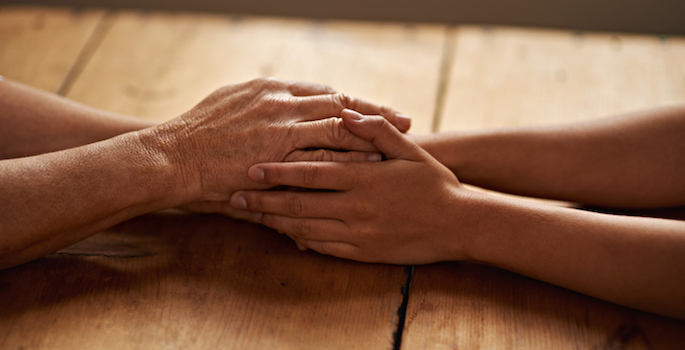 A cropped shot of a woman holding a loved one's hand in support