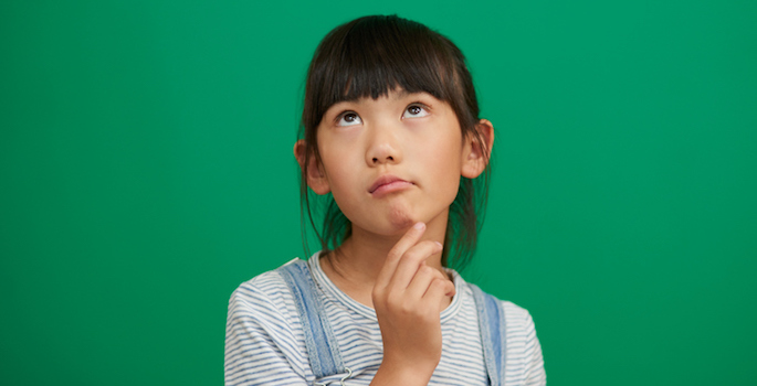 Asian girl looking thoughtful with hand in chin against a green background