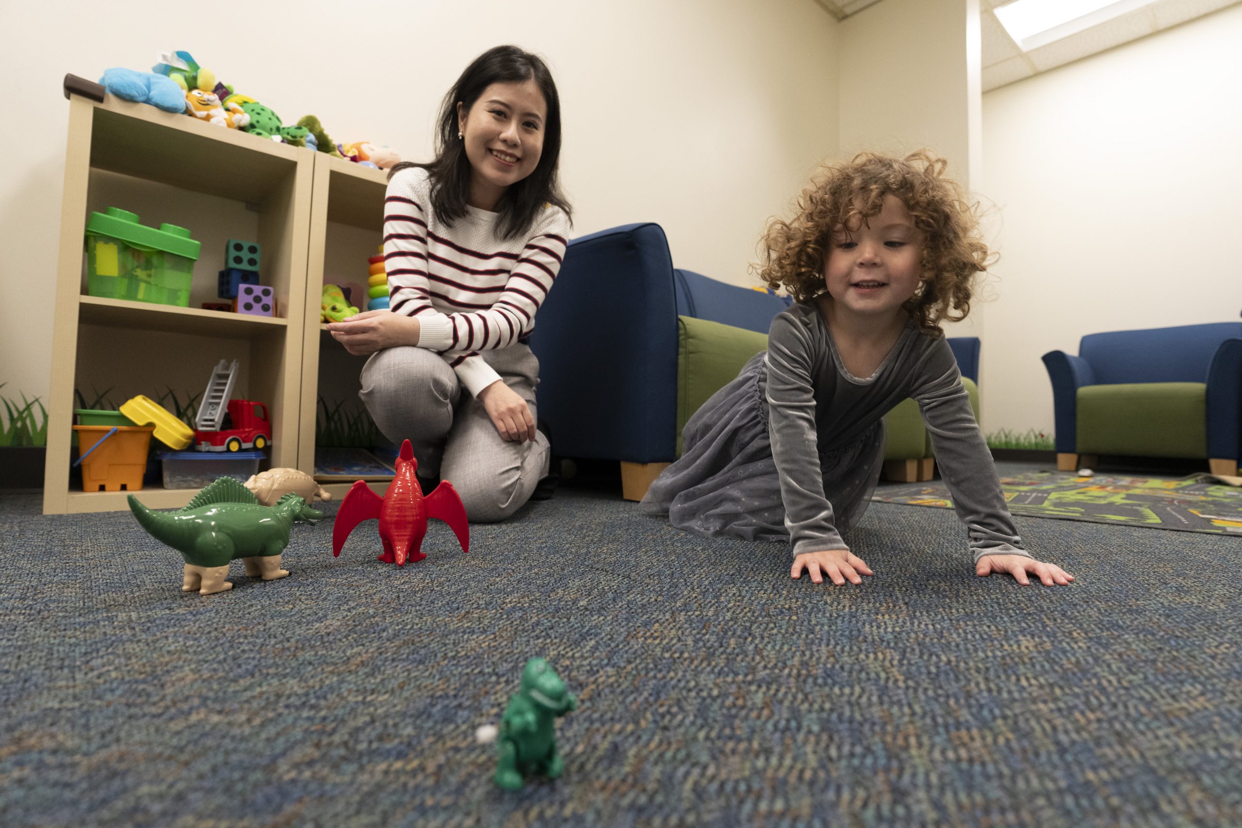 Wen Lu and child exploring toys on the floor in the Social Cognition Lab