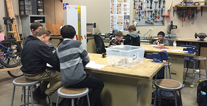 Young boys get hands-on engineering education at a work table in at STEM school