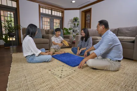 Jeong Oh Kim, senior lecturer in the department of English, with his family playing Yut Nori in their Zeppos College residence (Harrison McClary/Vanderbilt)