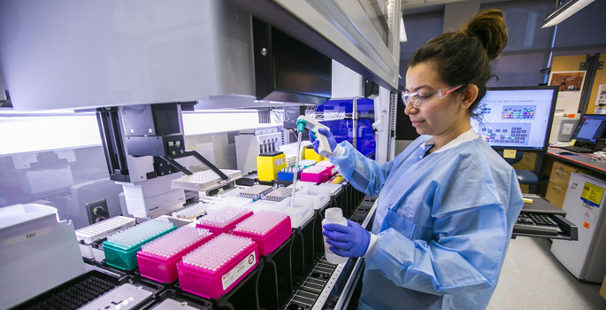 woman in lab with pipette and test tubes