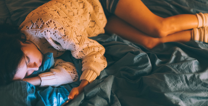 Depressed teenage girl at home using smartphone