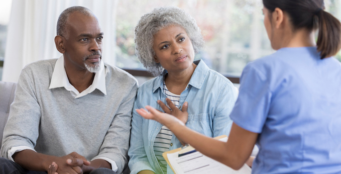 female physician explaining something to elderly african american couple in doctors office