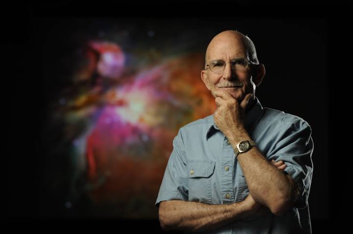 Bob O'Dell standing in front of image of Orion Nebula