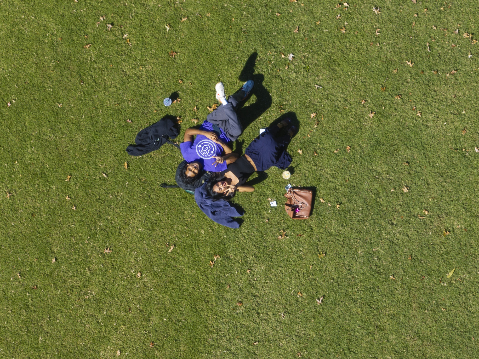 A drone image of two students laying on the grass on campus. 