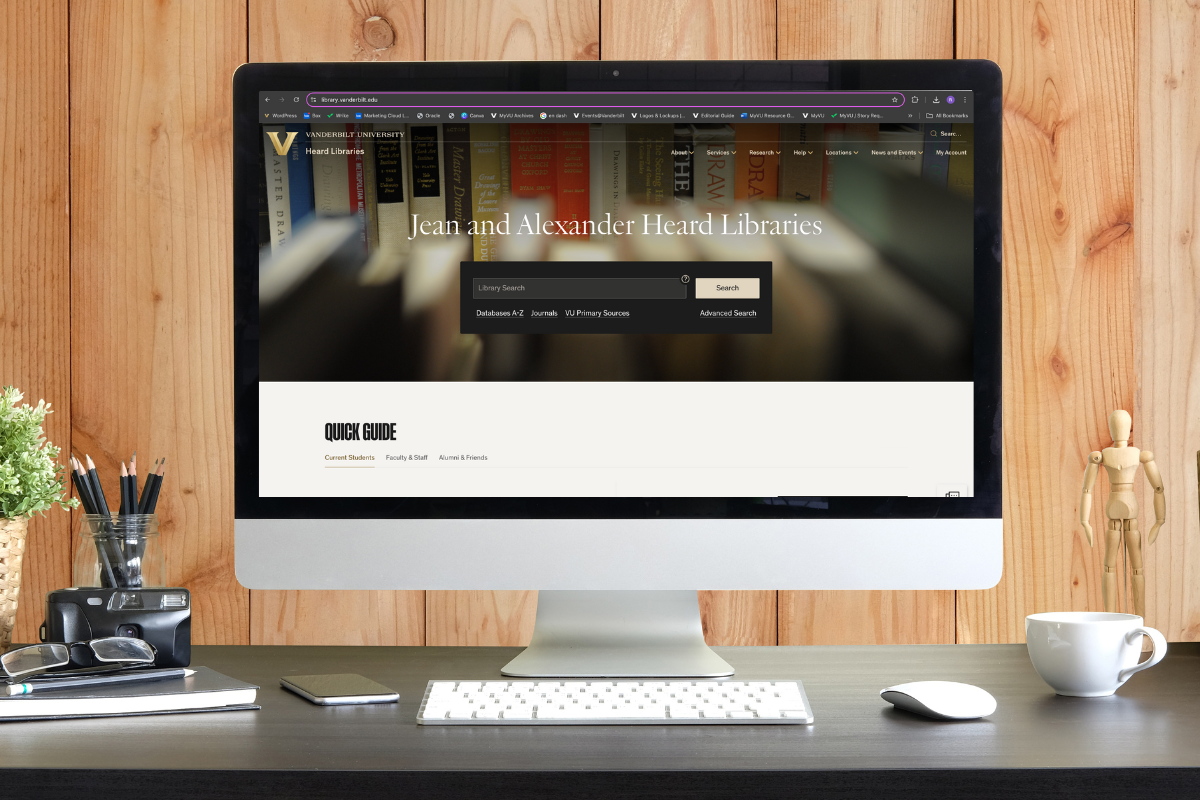 A computer monitor against a wood panel wall. The monitor is displaying the home page for the Jean and Alexander Heard Libraries.