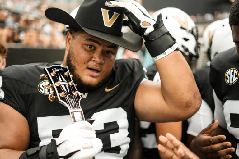 A football player dons the new turnover cowboy hat and guitar.