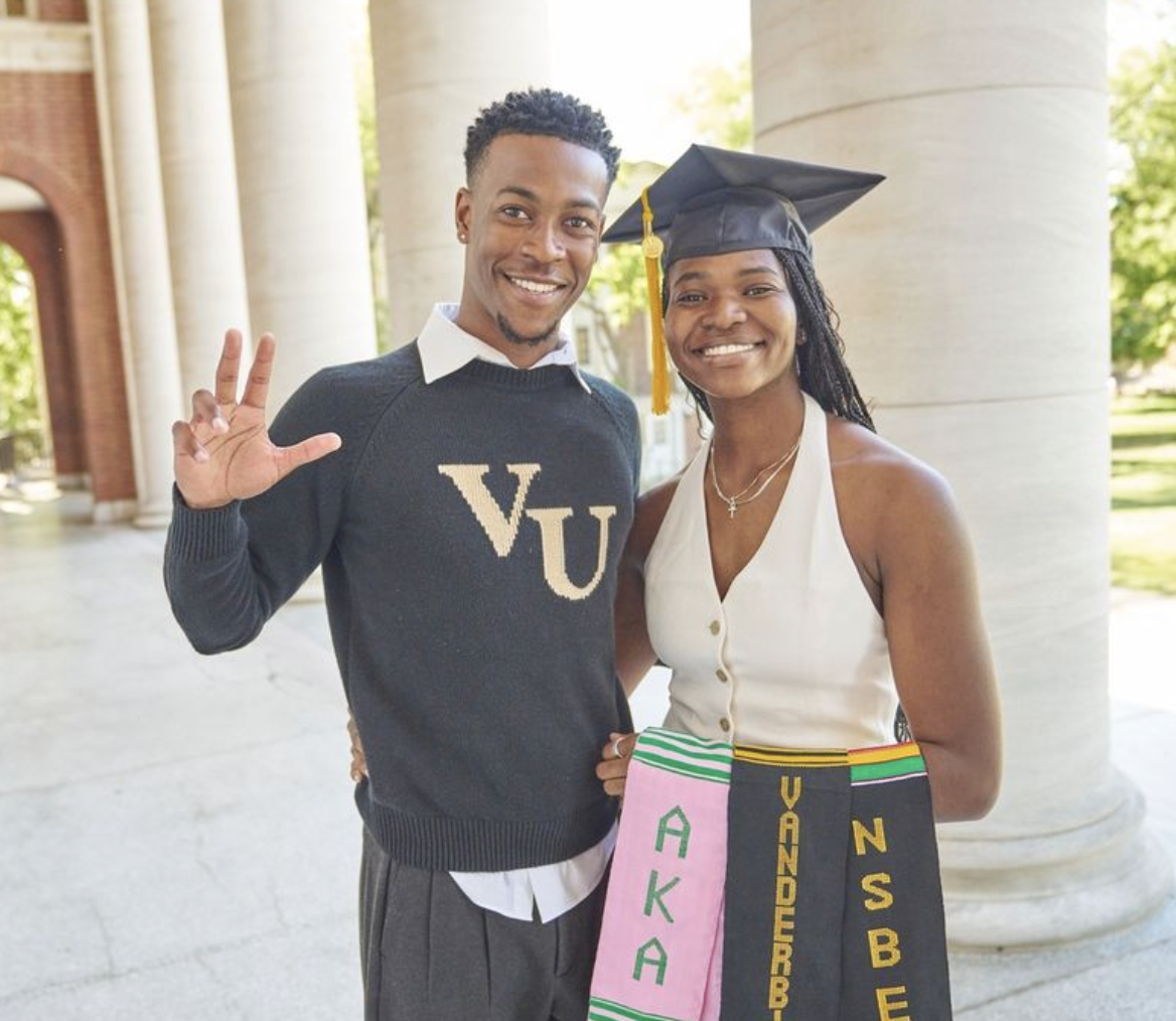 Two students pose for graduation photos on campus.