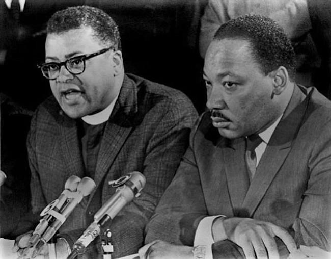 A black and white image shows Rev. James Lawson and Rev. Martin Luther King, Jr. at a speaking event. 
