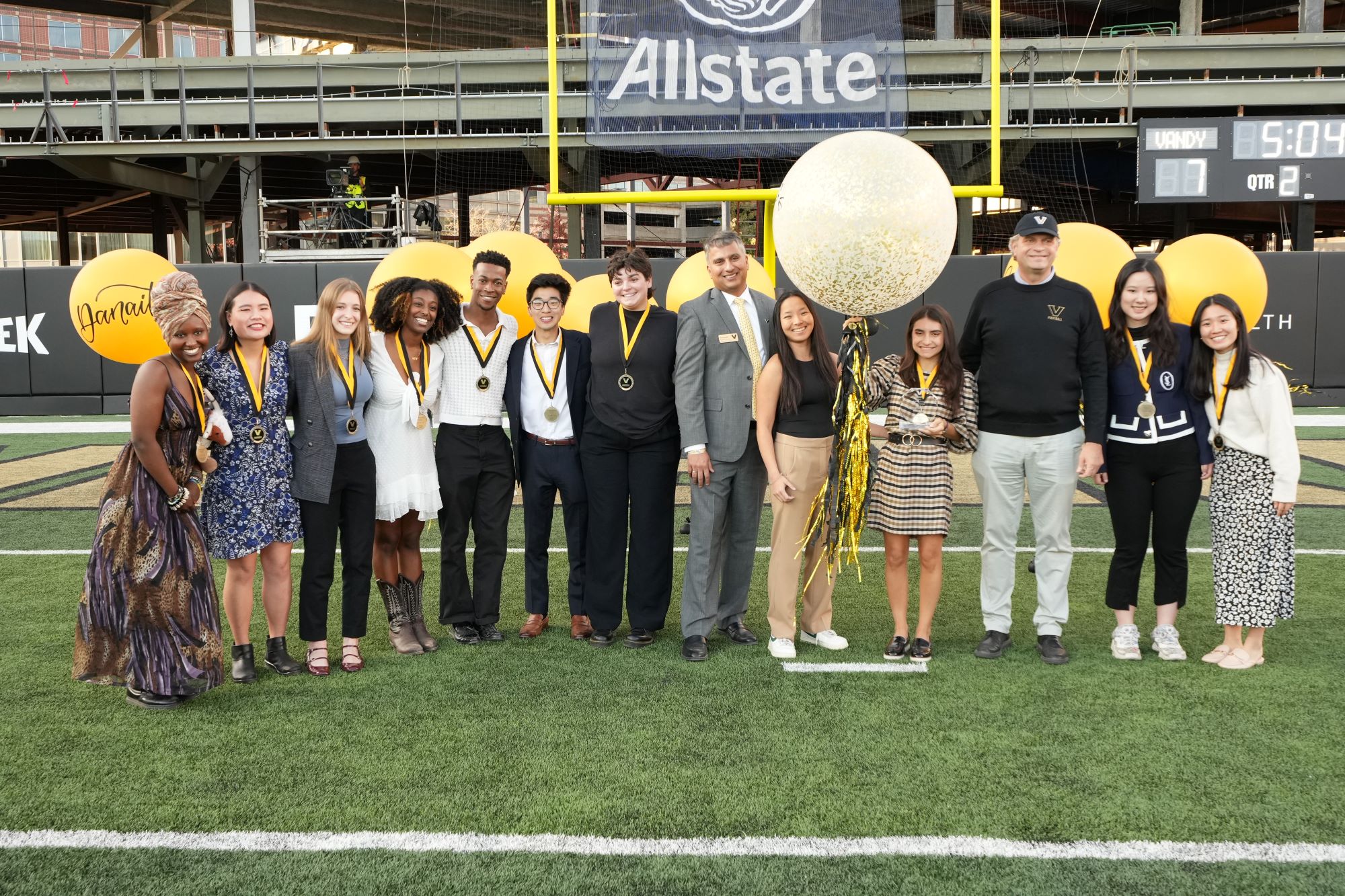 Class of 2024 Outstanding Senior nominees pose with Chancellor Daniel Diermeier and Vanderbilt Alumni Association Board President Anu Pardeshi on the football field during Homecoming Weekend 2023. 
